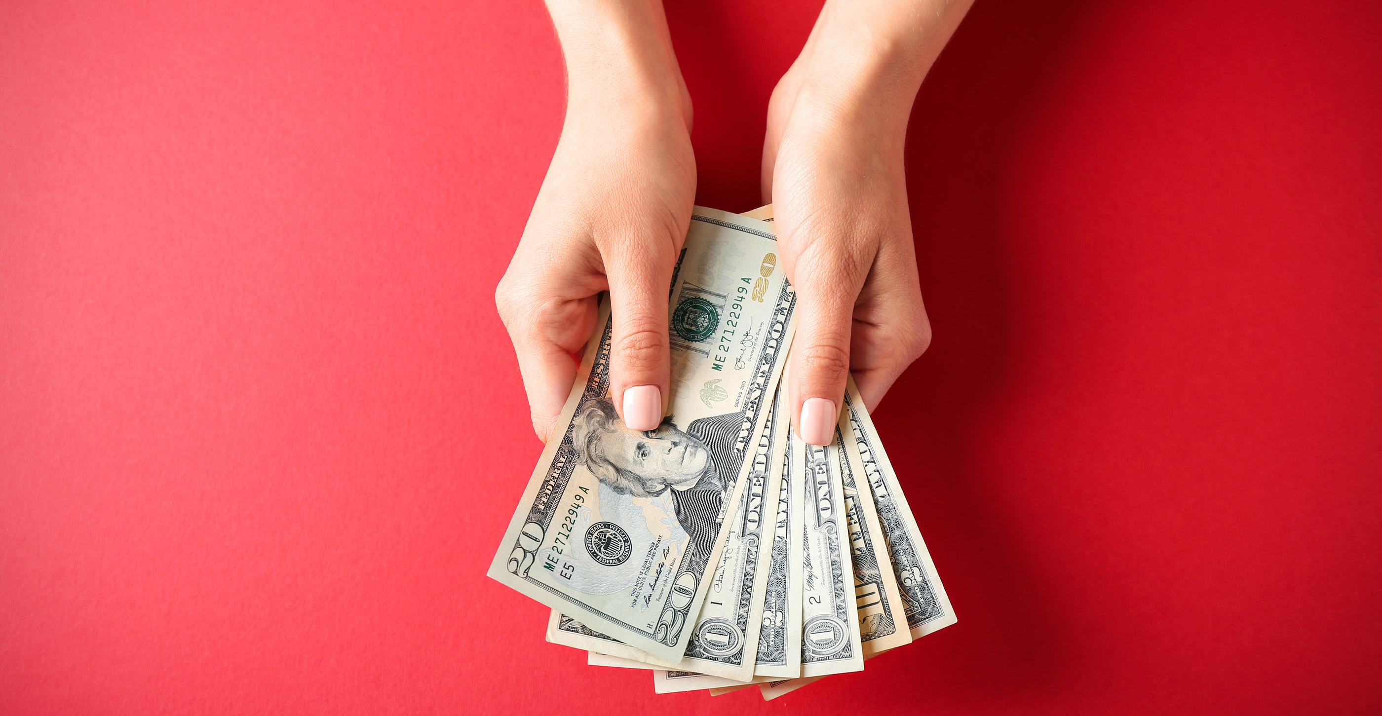 Woman hands holding money on red background